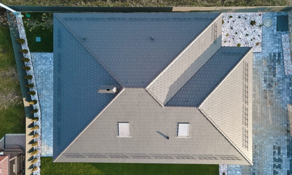 Aerial view of house roof top covered with ceramic shingles. Tiled covering of building under construction.