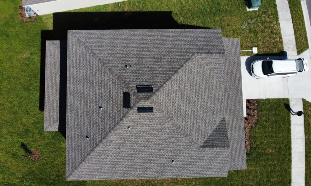 aerial drone photo of roof of modern house with white car in drive way